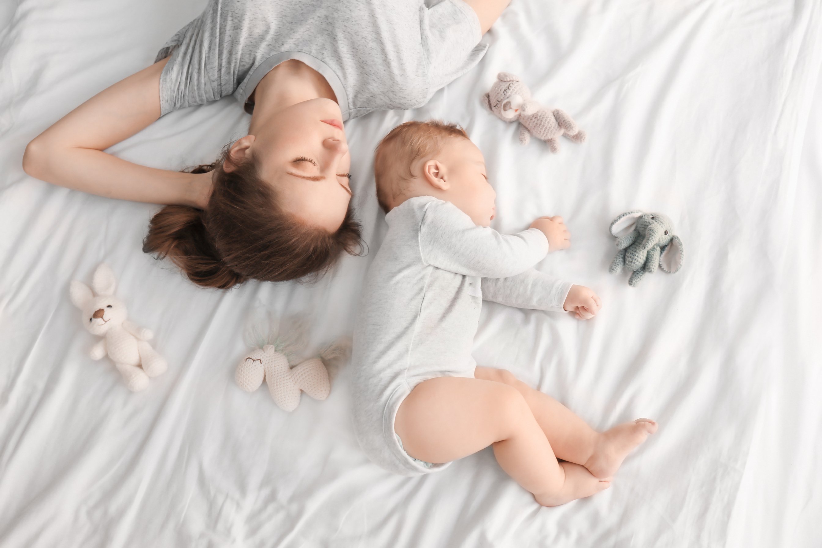 Mom and Baby Sleeping with Toys on Bed